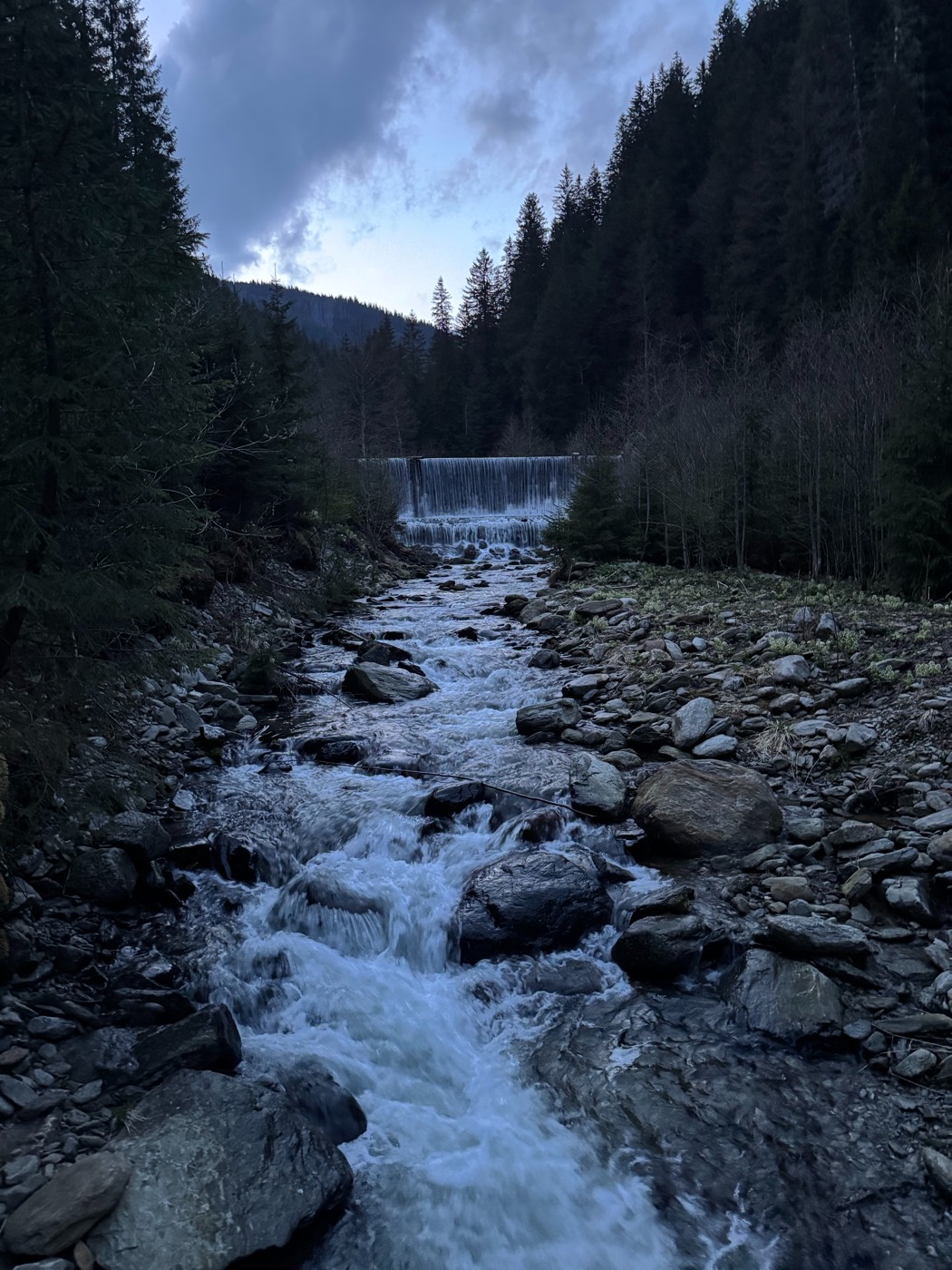 A mountain stream tumbling over a weir at dusk